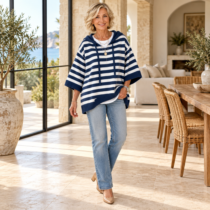Marine – Navy Blue Striped Poncho Sweater worn by a mature blonde woman in a Mediterranean interior